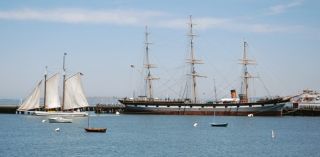 A view across the cove with scow schooner ALMA underway and BALCLUTHA moored at Hyde Street Pier.