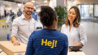 Image of a man and women speaking to an IKEA co-worker at the customer service counter