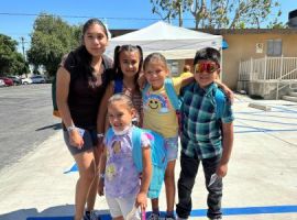 Community children posing with new backpacks filled with school supplies from Resource Fair. ...