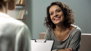 Young happy lady talking with psychologist at clinic, session of rehab therapy