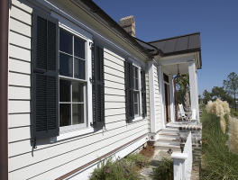 Image of the front of a house with clappboard siding and shutters.